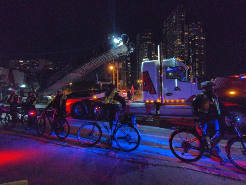 Bike police guard a truck carrying a milling machine.