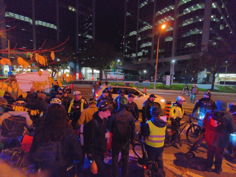 Police force protesters back onto the sidewalk.
