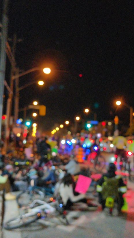 Protesters with their bikes lie down in the Bloor bike lanes in a "die-in". Blurred for privacy.